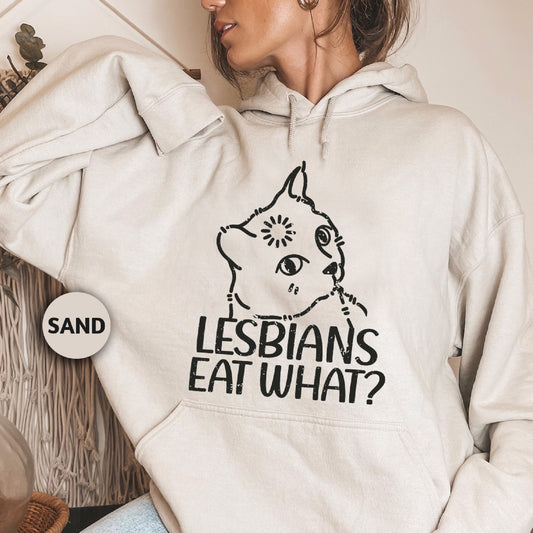 a woman wearing a white hoodie with the words lesbians eat what? on