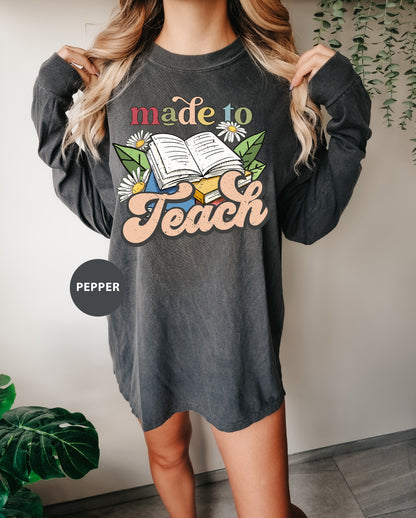 a woman wearing a sweatshirt that says made to teach