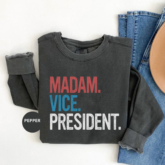 a shirt that says madam vice president next to a pair of jeans