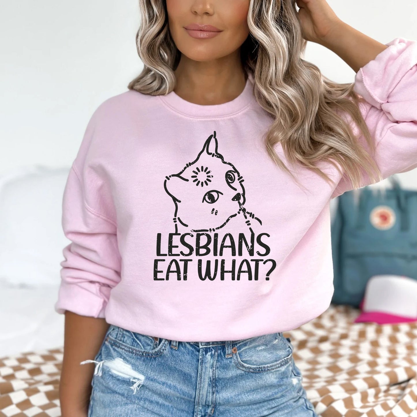 a woman wearing a pink sweatshirt that says lesbians eat what?