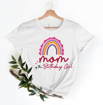 A white t-shirt with a colorful graphic design and text printed on it, hanging on a wooden hanger.