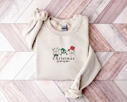 A beige sweater with a Christmas crew design printed on it, featuring three cartoon animal characters and the text "Christmas Crew".
