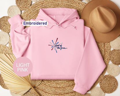 a pink hoodie with a graphic design, a brown hat, and a straw hat, all arranged on a woven mat.