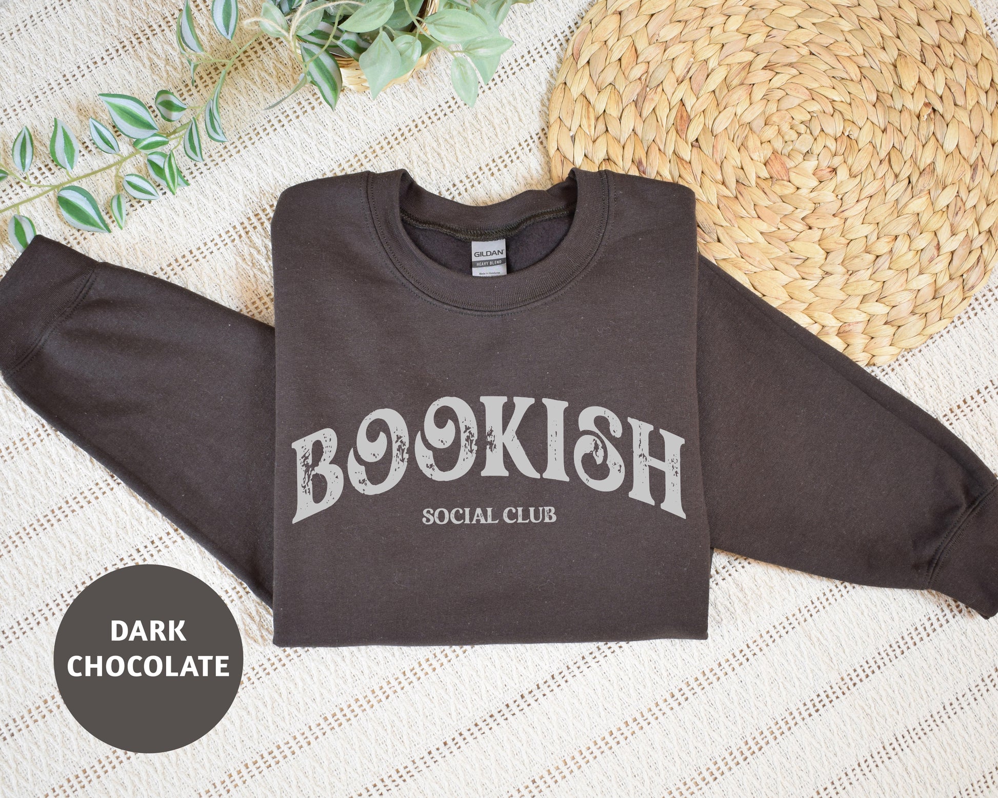 a bookish social club sweatshirt sitting on a bed next to a straw hat