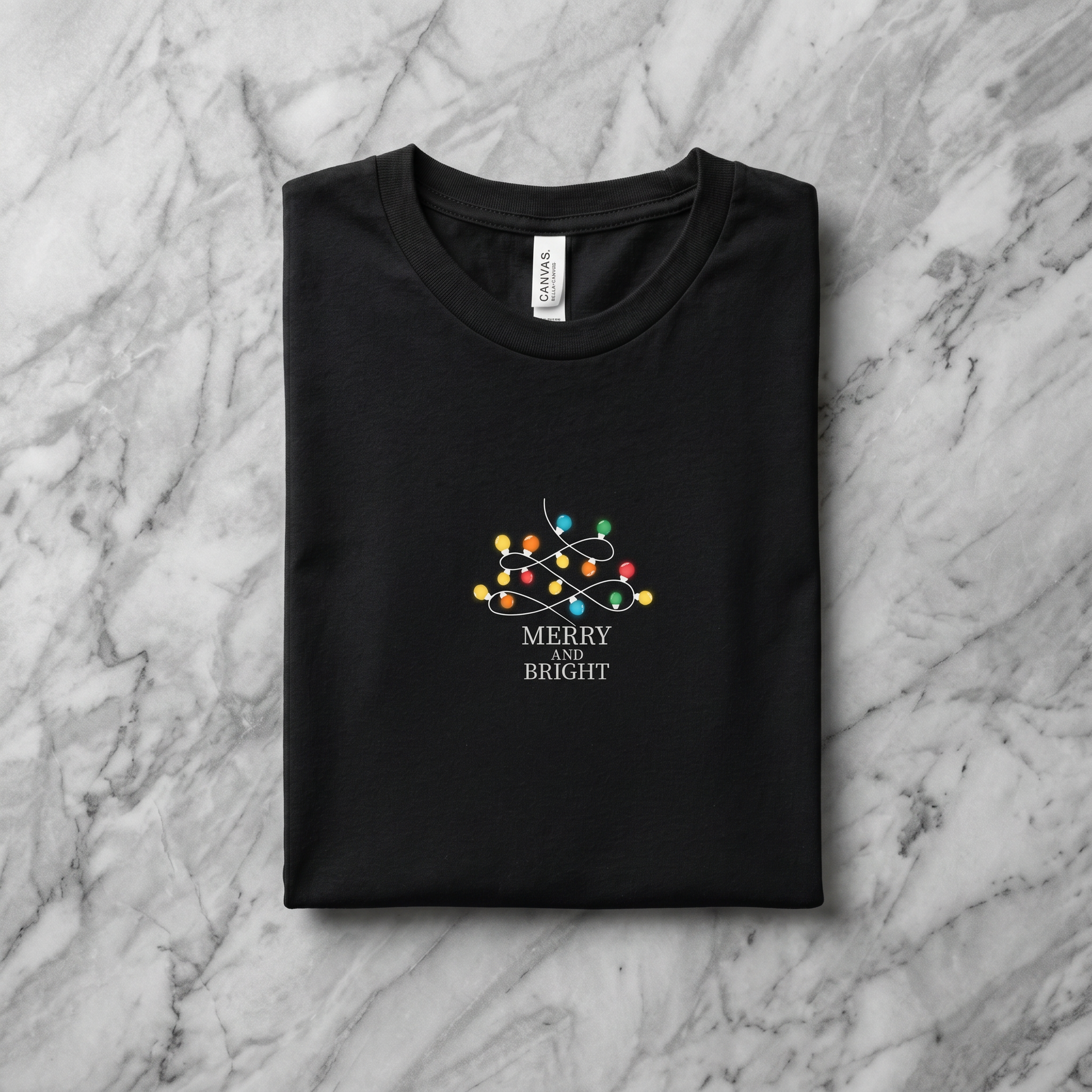 A black t-shirt with a graphic design on it, featuring a Christmas tree with colorful lights and the text "MERRY on BRIGHT" printed on it.