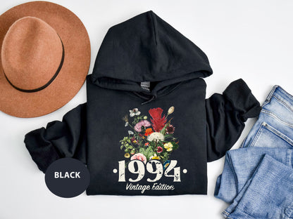 a black hoodie with flowers on it next to a hat