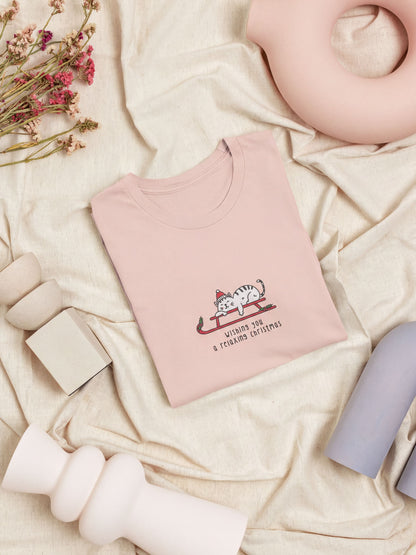 a pink t-shirt with a cat graphic and text, along with some other items such as a vase, a teapot, and a pink ceramic object.