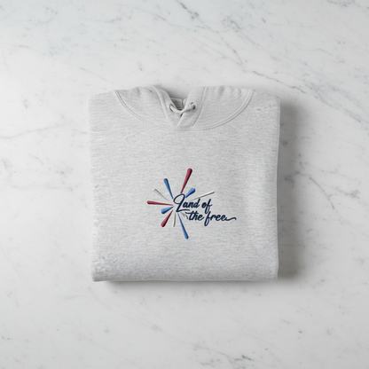 A gray hoodie with a graphic design and text printed on it, laid out on a marble surface.