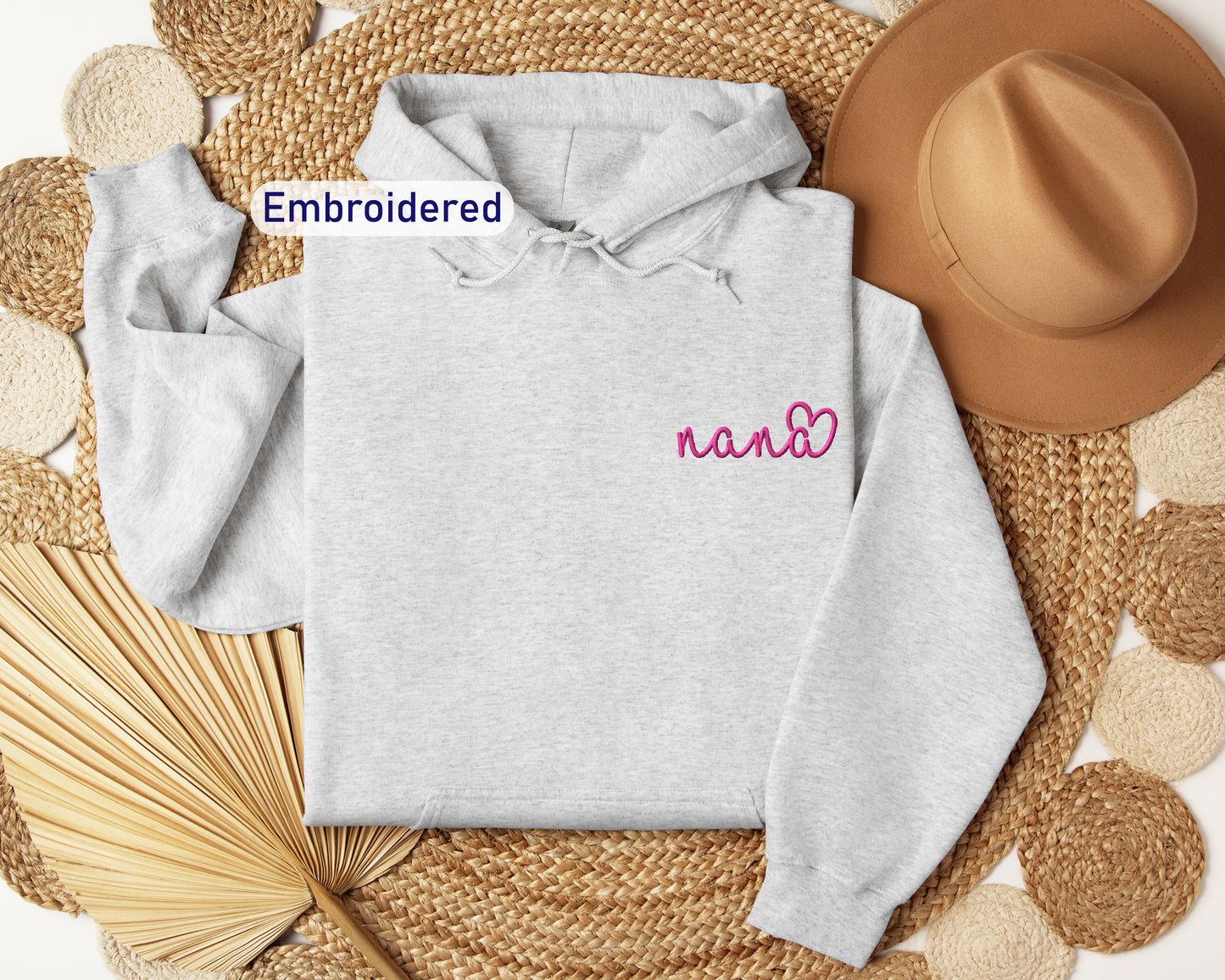 a white hoodie with embroidered name next to a straw hat