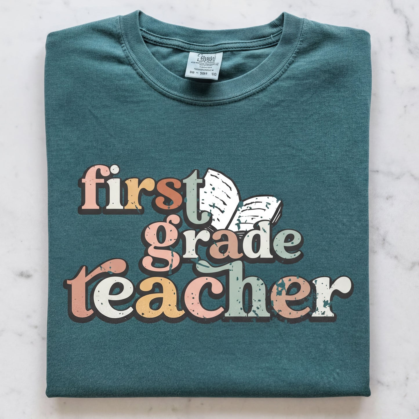 A green t-shirt with the text "first grade teacher" printed on it.