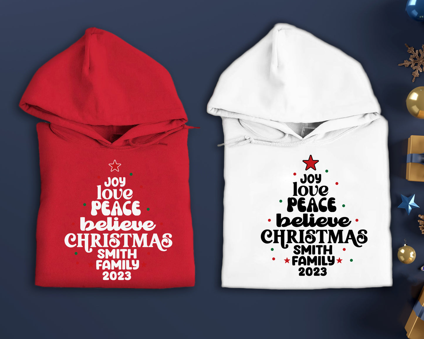 two hooded sweatshirts with Christmas-themed text printed on them, placed on a blue background.