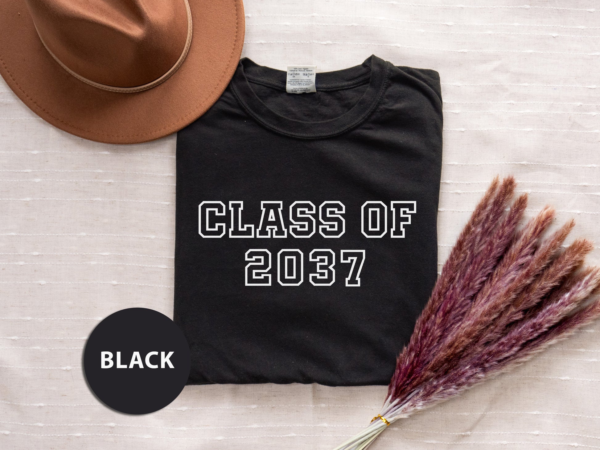 a t - shirt that says class of 2021 next to a hat