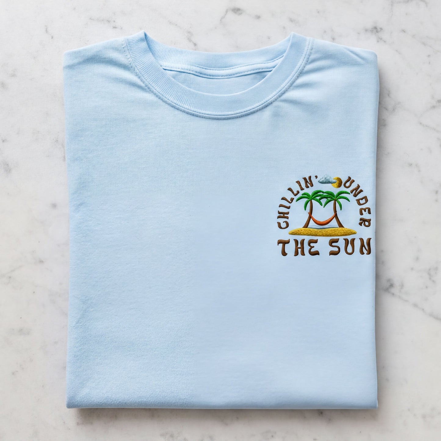 A light blue t-shirt with a graphic design on the front, featuring a palm tree and the text "Chillin' under the sun".
