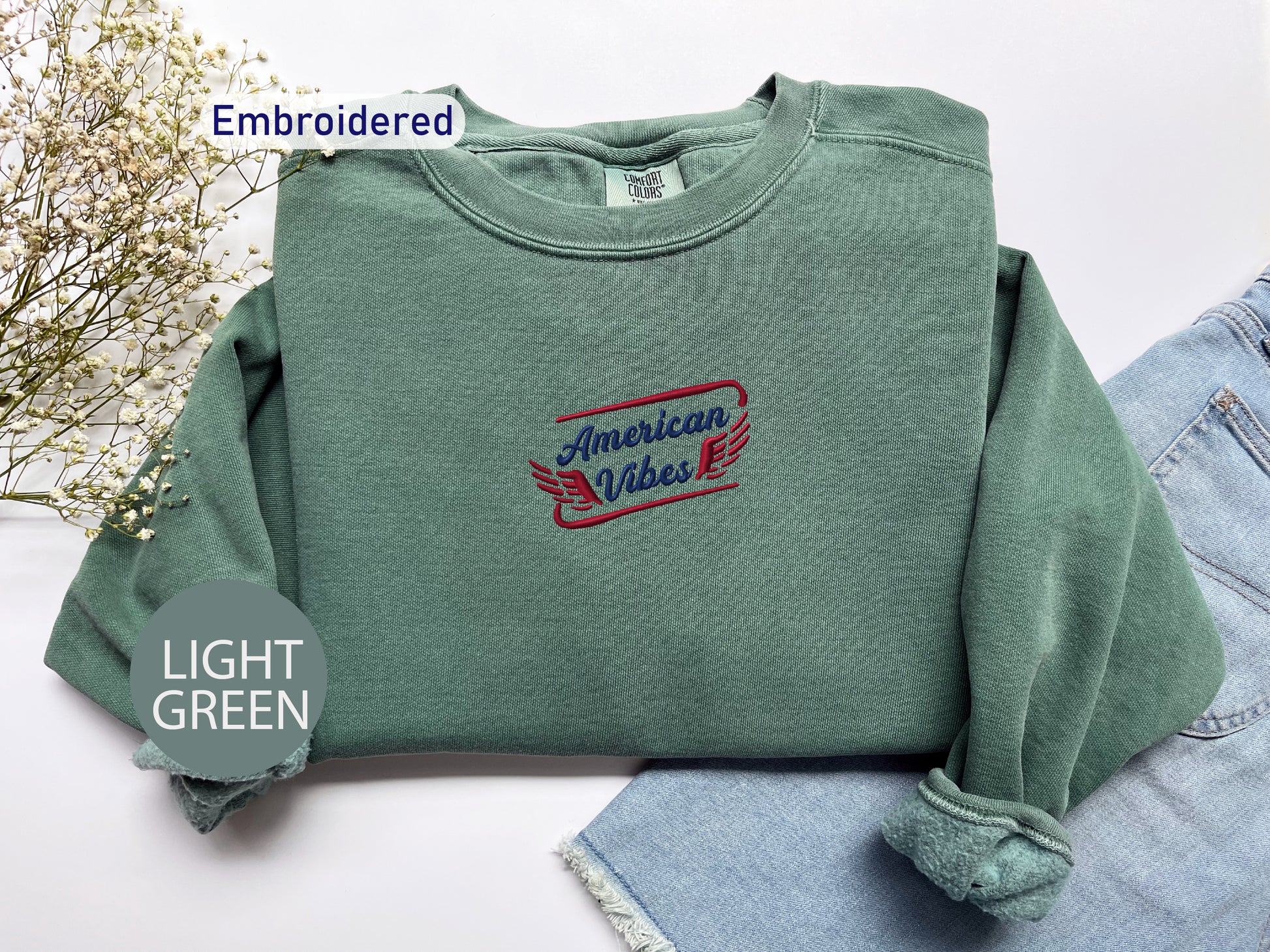 a green sweatshirt with a red and blue embroidered design on it, along with a pair of denim jeans and a light green circular object labeled "LIGHT GREEN".