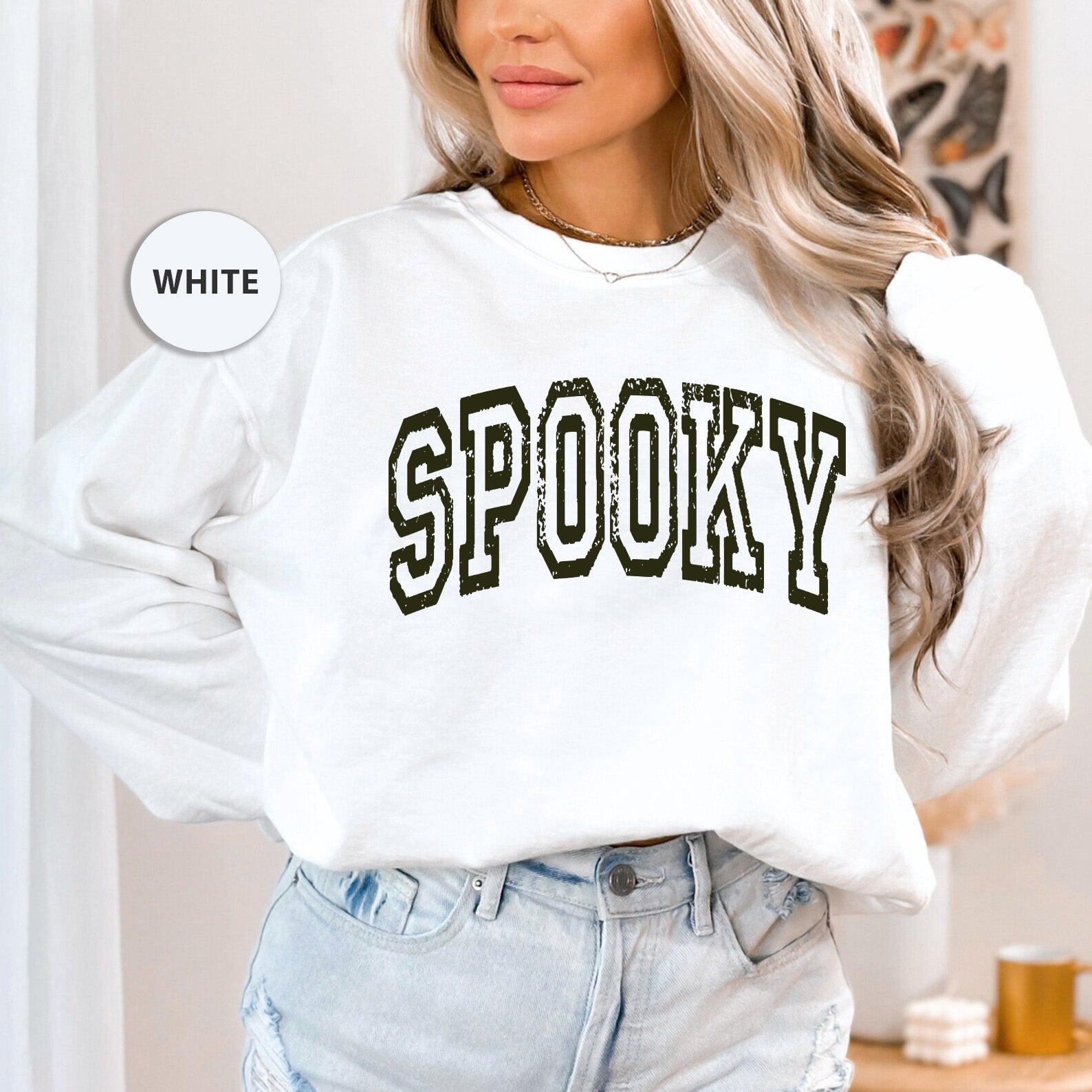 a woman wearing a white sweatshirt with the word spooky on it