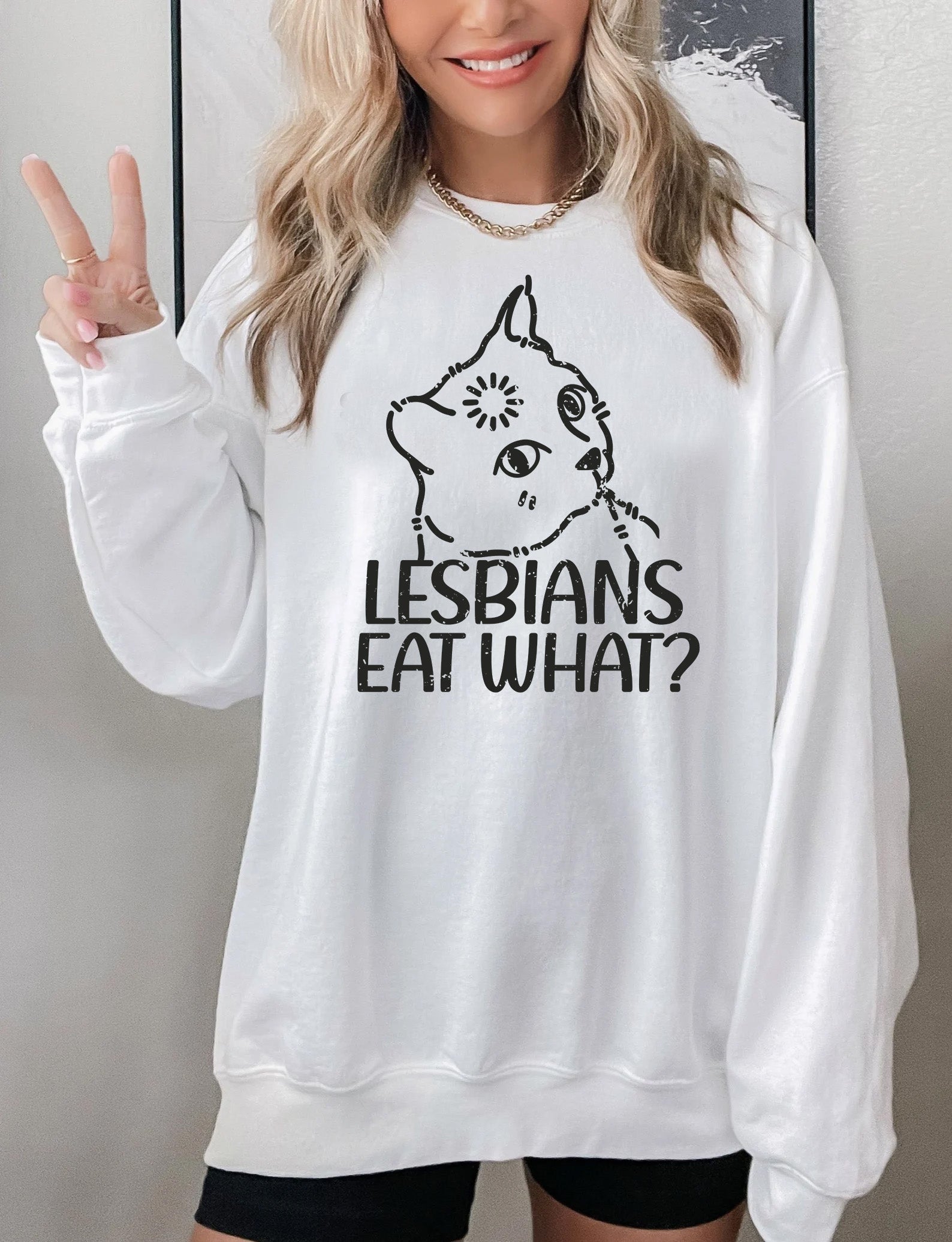 a woman wearing a white sweatshirt that says lesbians eat what?