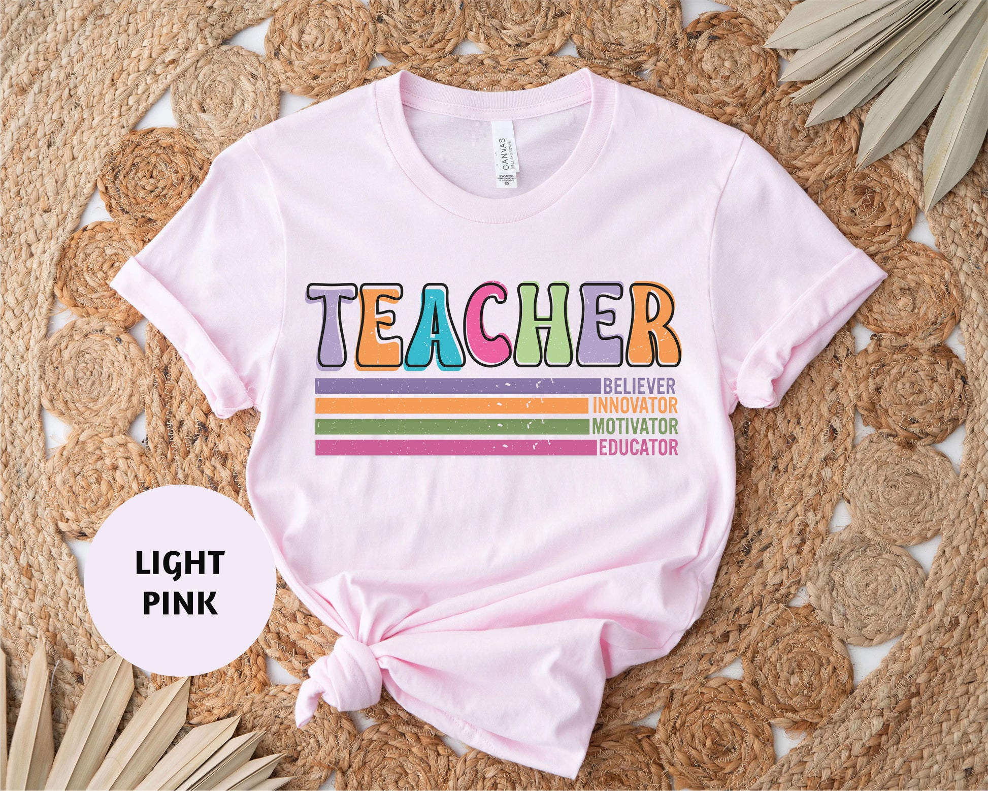 a pink teacher shirt with a rainbow design