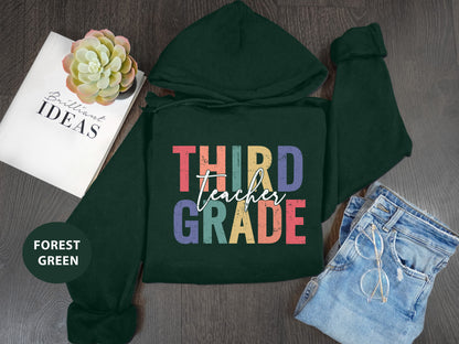 a green hoodie with the words third grade printed on it