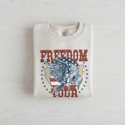 A white sweatshirt with a graphic design featuring an eagle and the text "FREEDOM TOUR" printed on it.