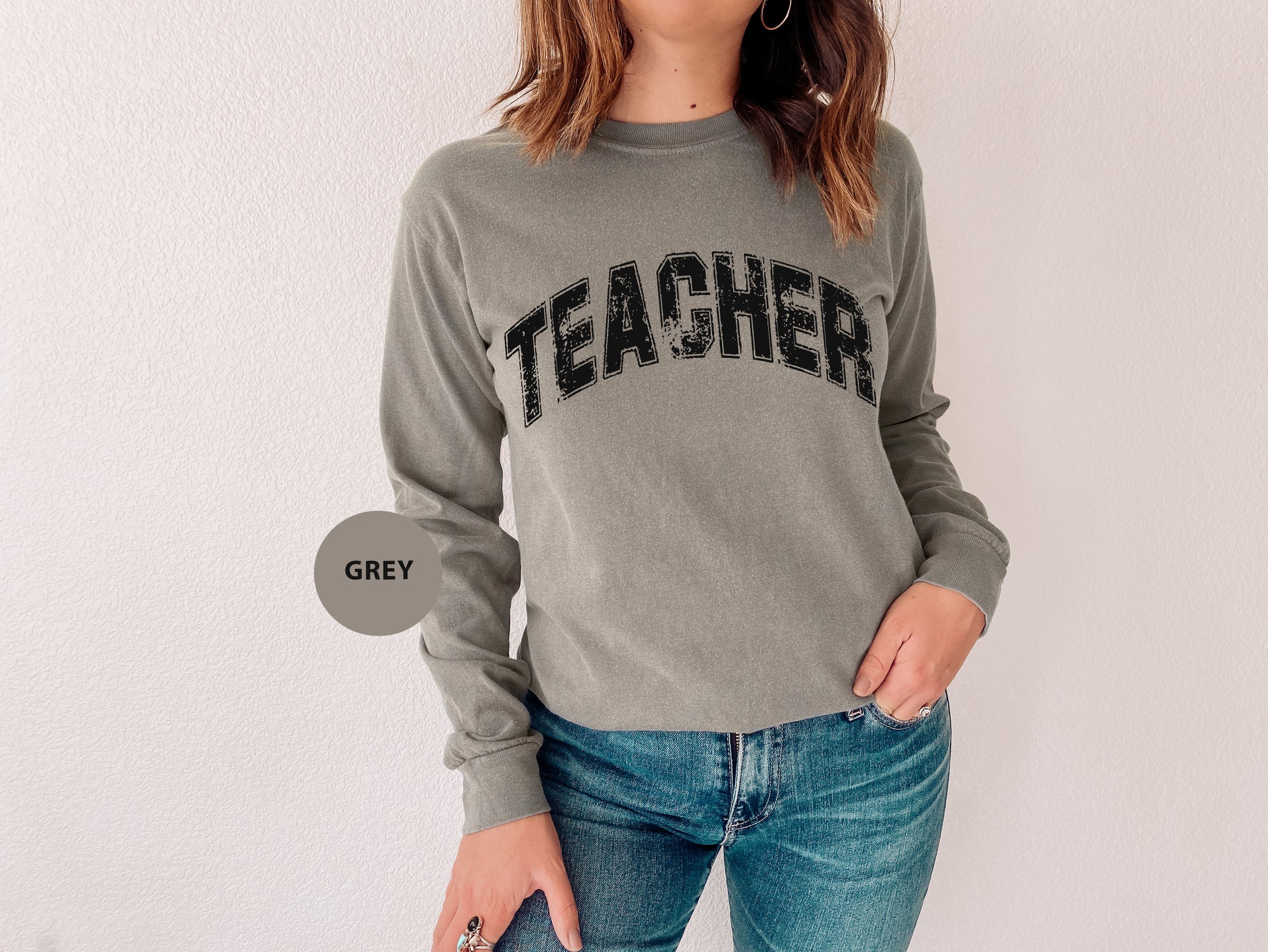 a woman wearing a grey sweatshirt with the word teacher on it