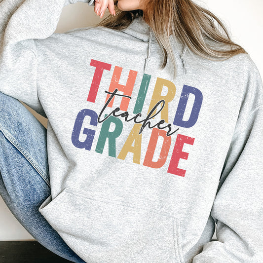 a woman wearing a sweatshirt that says third grade