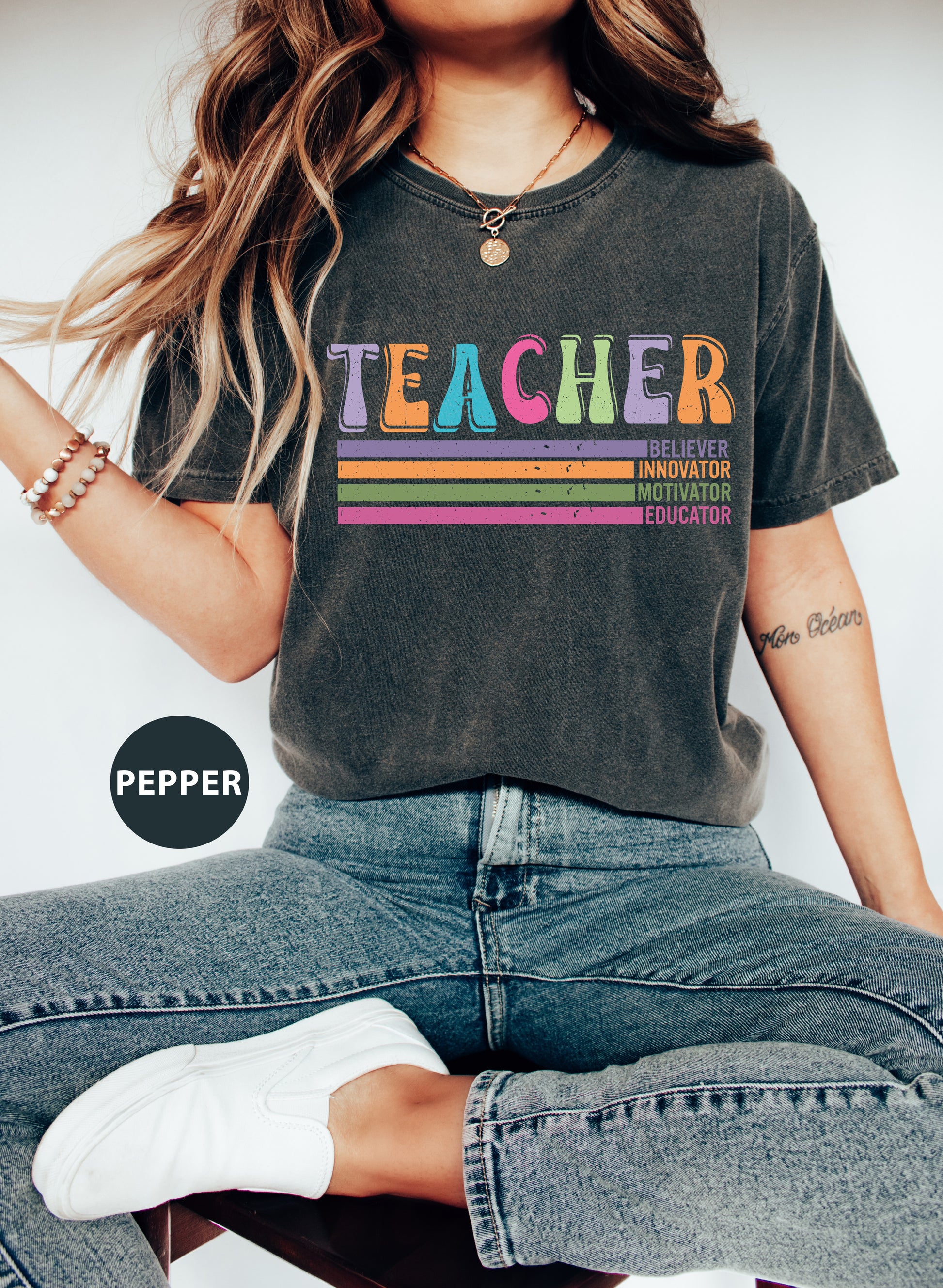 a woman sitting on a stool wearing a teacher t - shirt