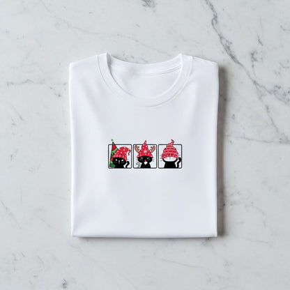 A white t-shirt with a graphic design featuring three cartoon cats wearing red hats.