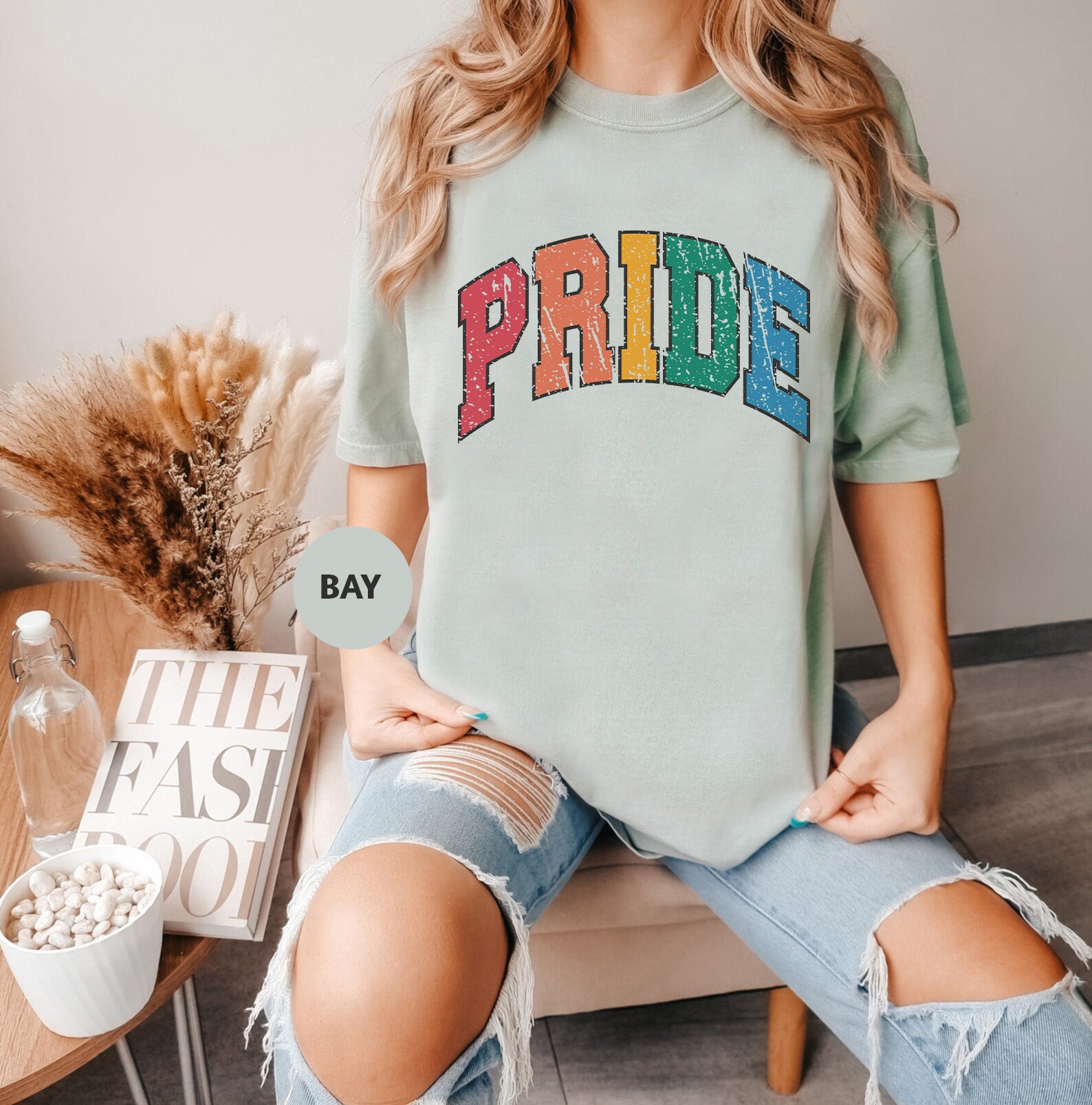 a woman sitting on a chair wearing a pride shirt