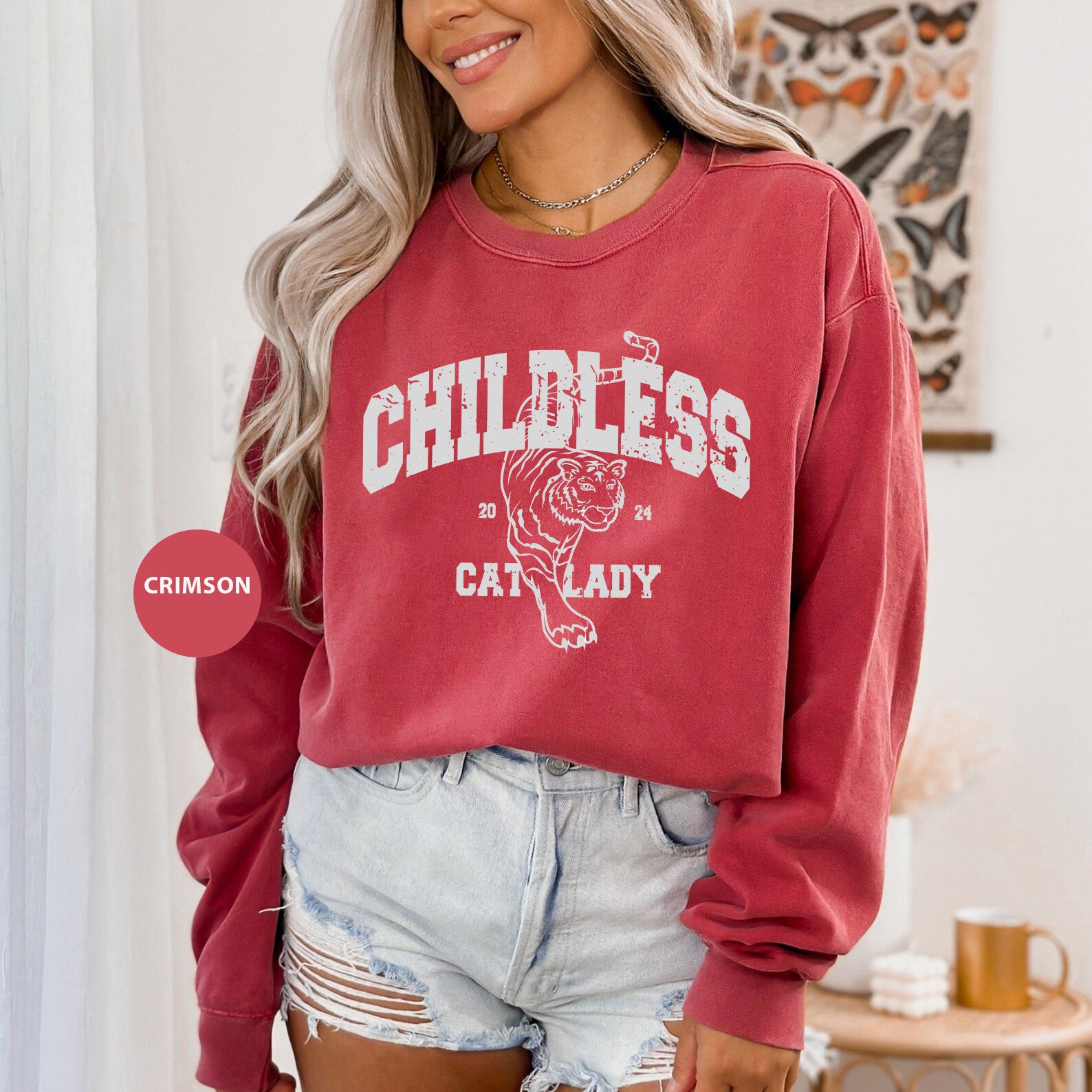 a woman wearing a red sweatshirt and denim shorts