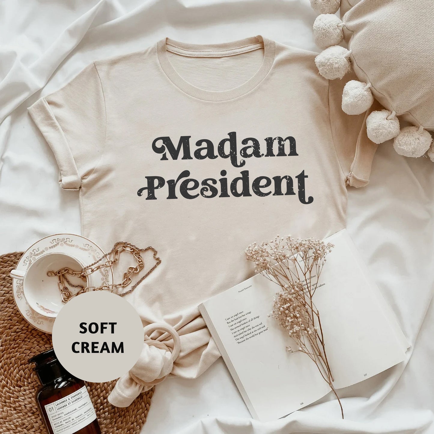 a t - shirt that says madam president sits on a bed next to a book