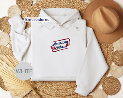 a white hoodie with an embroidered design, a brown hat, and a straw hat, all arranged on a woven mat.