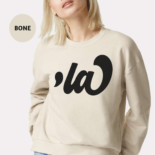 a woman with blonde hair wearing a white sweater with the word la on it