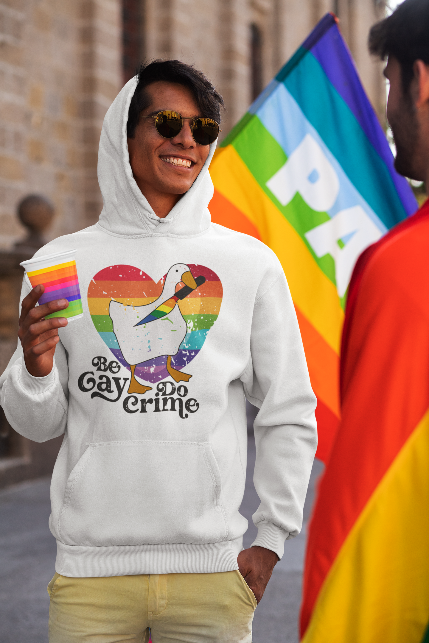 a man wearing a gay pride hoodie holding a rainbow flag