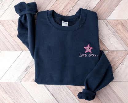 a little star sweatshirt laying on a wooden floor