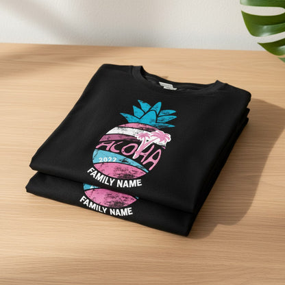 A black t-shirt with a graphic design of a pineapple and the word "Aloha" printed on it, along with the text "FAMILY NAME" printed below.