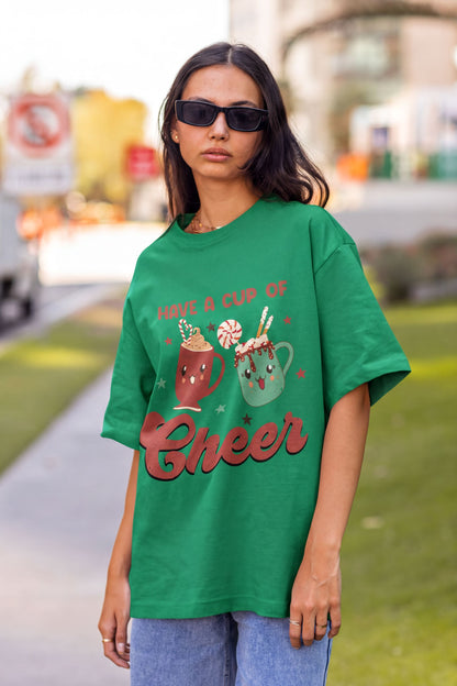 A woman wearing a green t-shirt with a graphic design of two smiling cupcakes and the text "Have a cup of cheer".