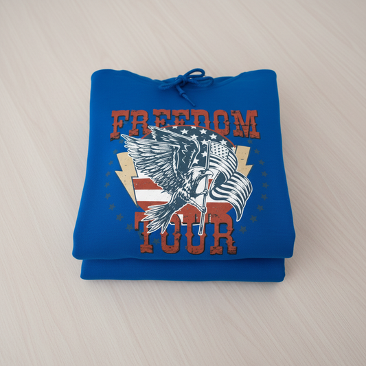 A blue hoodie with a graphic design featuring a bird, an eagle, and the text "FREEDOM TOUR" printed on it.