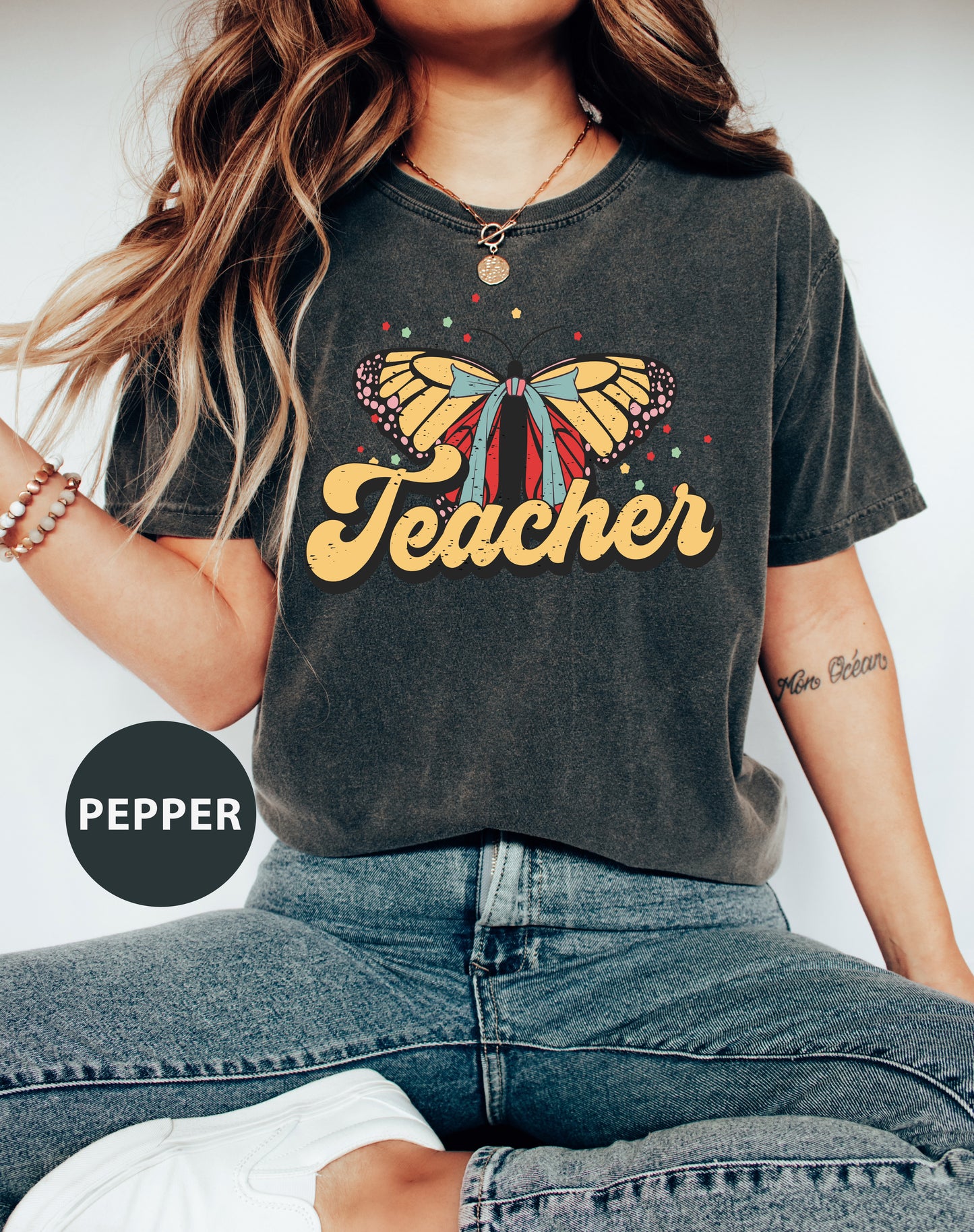 a woman wearing a teacher shirt with a butterfly on it