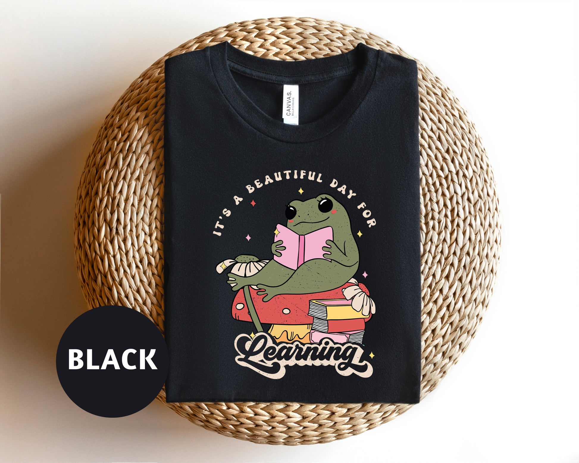 a black t - shirt with a dinosaur reading a book