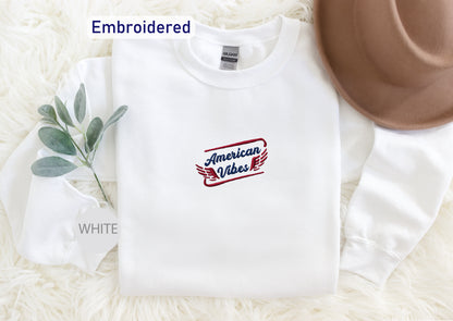 A white long-sleeved shirt with a red and blue embroidered logo that says "American Vibes" on it, along with a brown hat and a white sock.