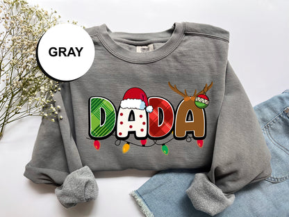 A gray sweatshirt with a colorful design featuring the word "DADA" in a festive style, along with a Santa hat and Christmas lights.