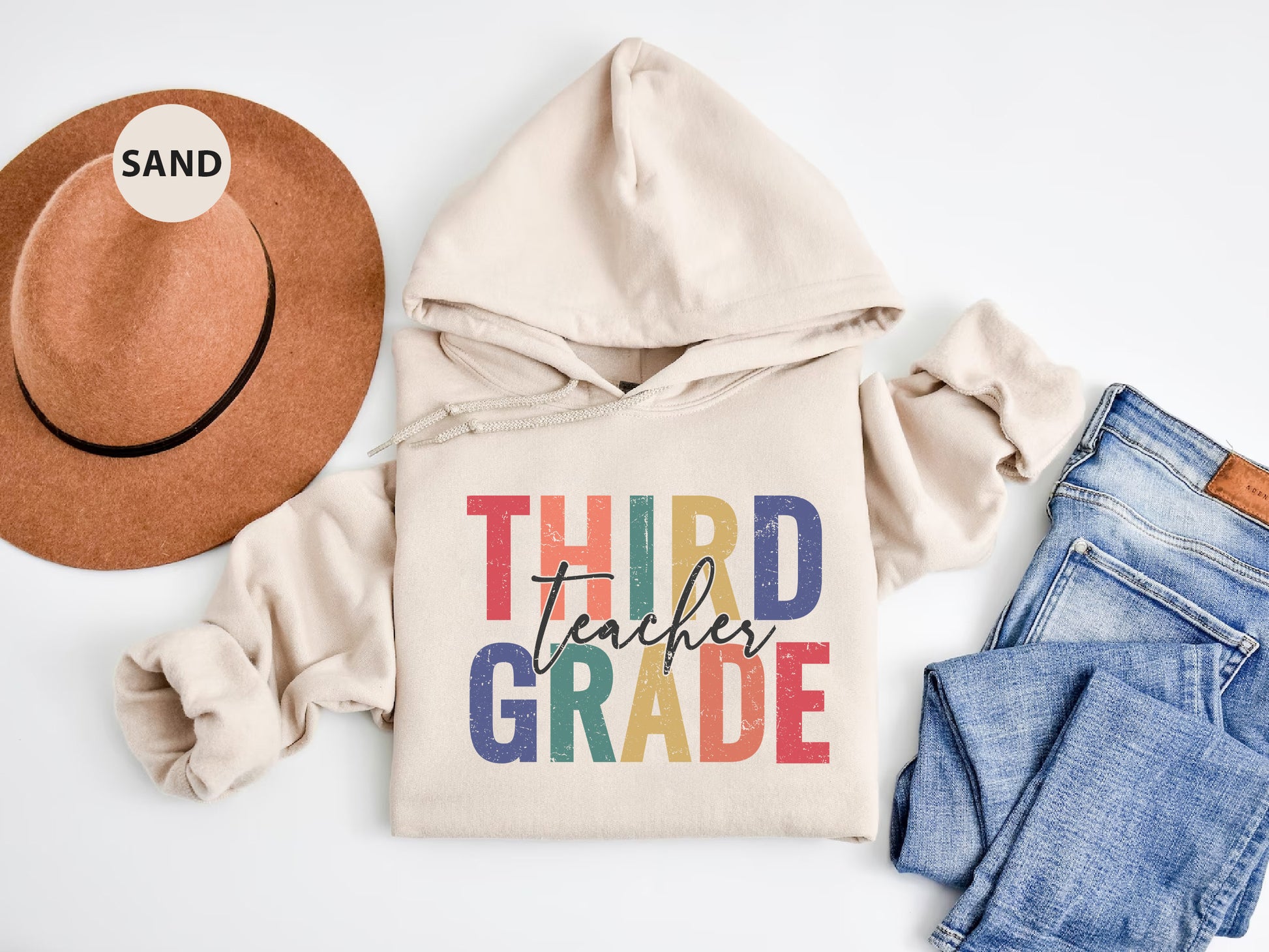 a white hoodie with the words third grade on it next to a pair of