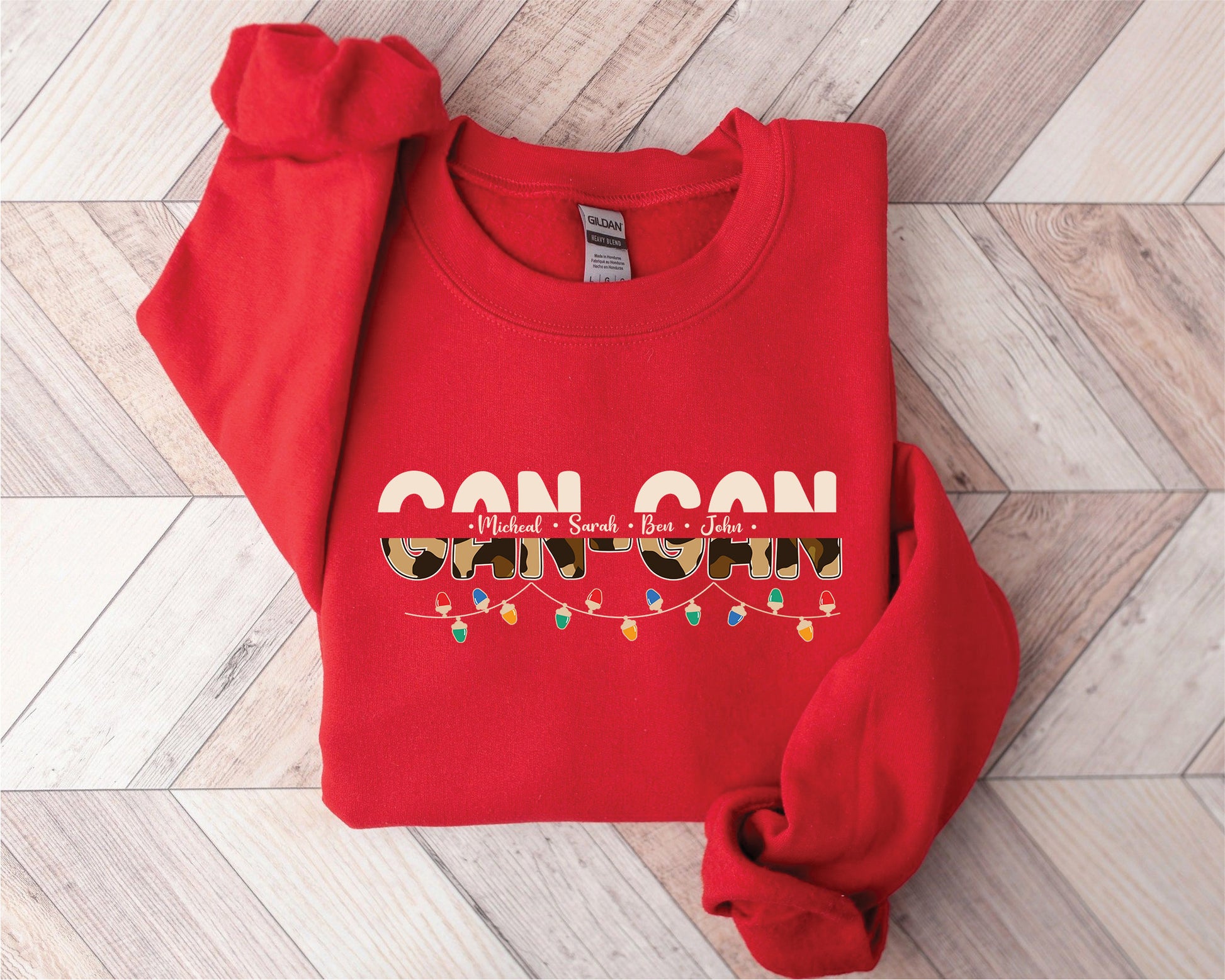 A red sweatshirt with the text "CAN CON" printed on it, along with the names "Michael, Sarah, Ben, John" and a pattern of lights.