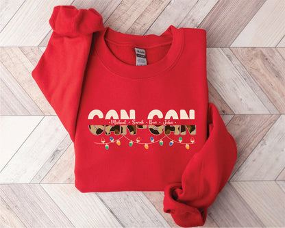 A red sweatshirt with the text "CAN CON" printed on it, along with the names "Michael, Sarah, Ben, John" and a pattern of lights.