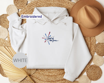 a white hoodie with a graphic design, a brown hat, and some woven straw items arranged on a woven mat.