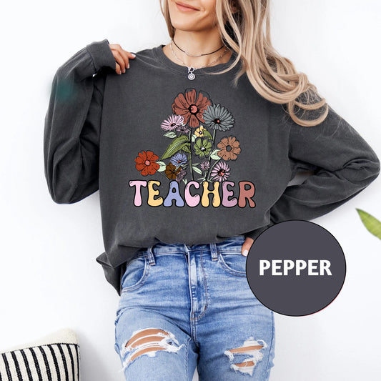 a woman wearing a teacher sweatshirt with flowers on it