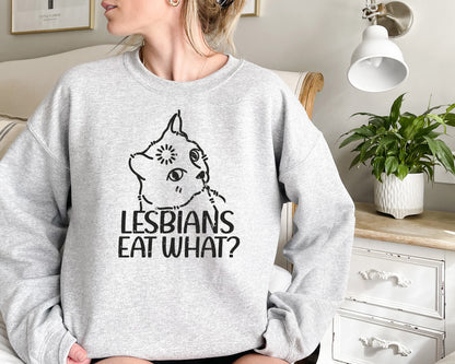 a woman sitting on a bed wearing a grey sweatshirt with the words lesbians eat