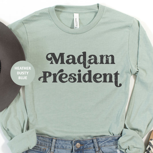 a green shirt that says madam president next to a hat