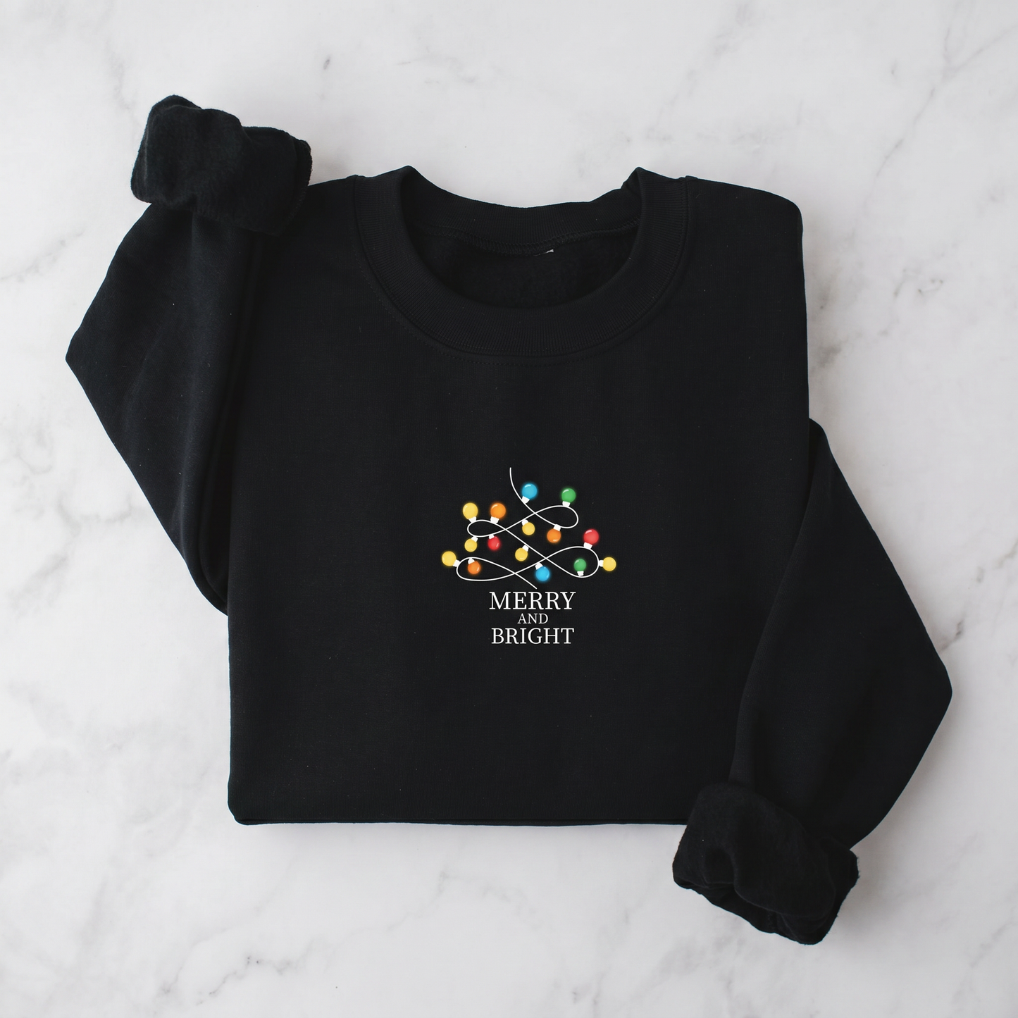 A black sweater with a white and colorful Christmas-themed design and the text "MERRY BRIGHT" printed on it.