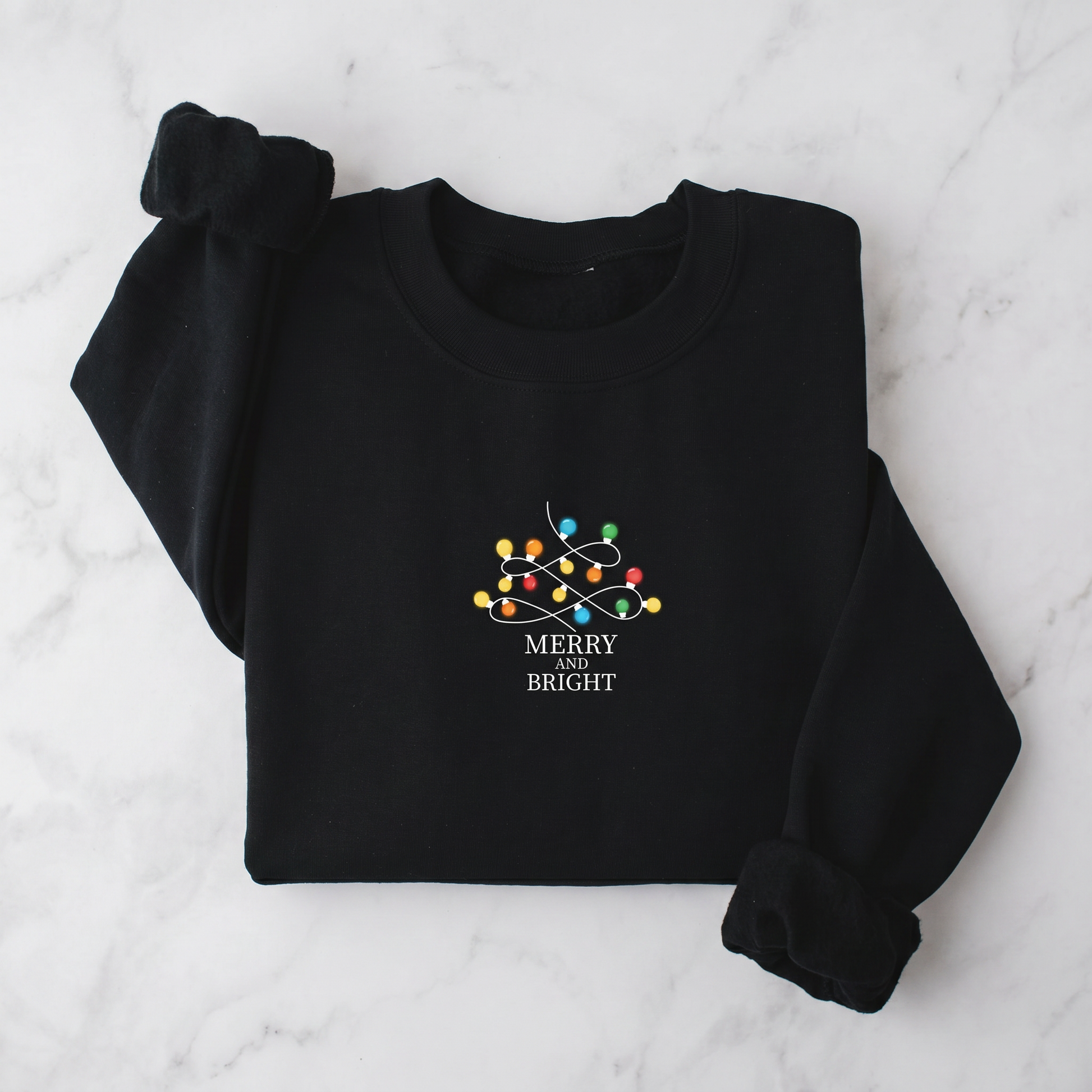 A black sweater with a white and colorful Christmas-themed design and the text "MERRY BRIGHT" printed on it.